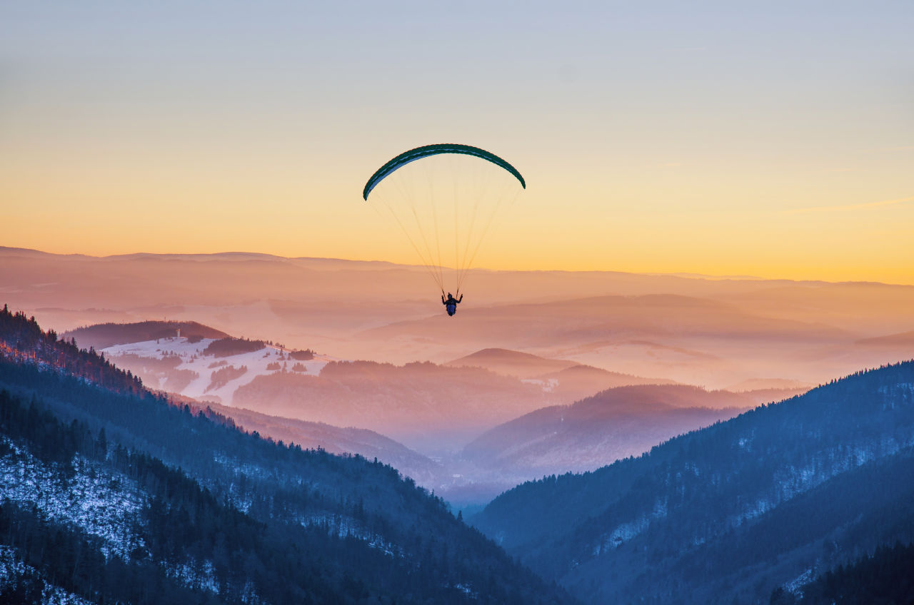 A person paragliding at sunset in the mountains